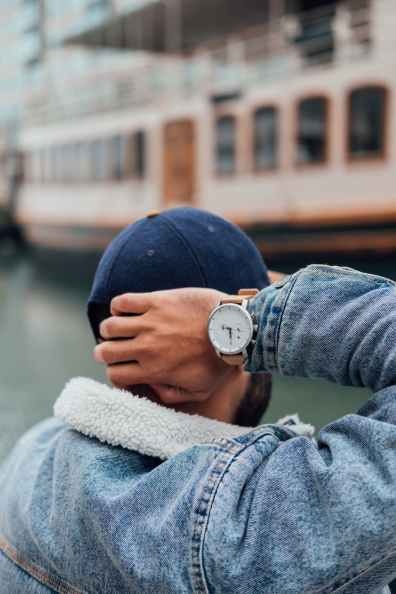 person wearing blue denim jacket and silver round analog watch